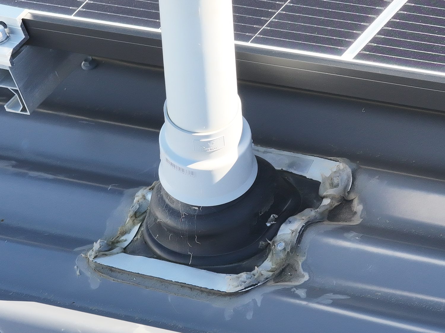 Tele detail of the same vent penetration showing weathered, cracked perimeter sealant and deposits on the rubber collar